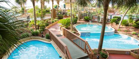 A pool area with multiple hot tubs and a wooden deck.