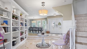 A spacious room with a dining area, a white bookshelf, and a round table with chairs.