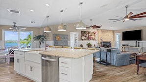 A spacious kitchen with a large island, white cabinetry, and a view to the outdoors.