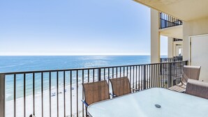 A balcony with a glass table and chairs overlooking a beach. - PHOENIX V..GULF FRONT..10' CEILINGS..WKLY DISCOUNTS..RESERVED COVERED PARKING. (Orange Beach)