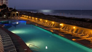 A swimming pool with lounge chairs and a view of the ocean at night. - PHOENIX V..GULF FRONT..10' CEILINGS..WKLY DISCOUNTS..RESERVED COVERED PARKING. (Orange Beach)