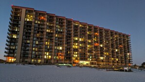 A high-rise hotel with multiple floors, balconies, and illuminated windows. - PHOENIX V..GULF FRONT..10' CEILINGS..WKLY DISCOUNTS..RESERVED COVERED PARKING. (Orange Beach)