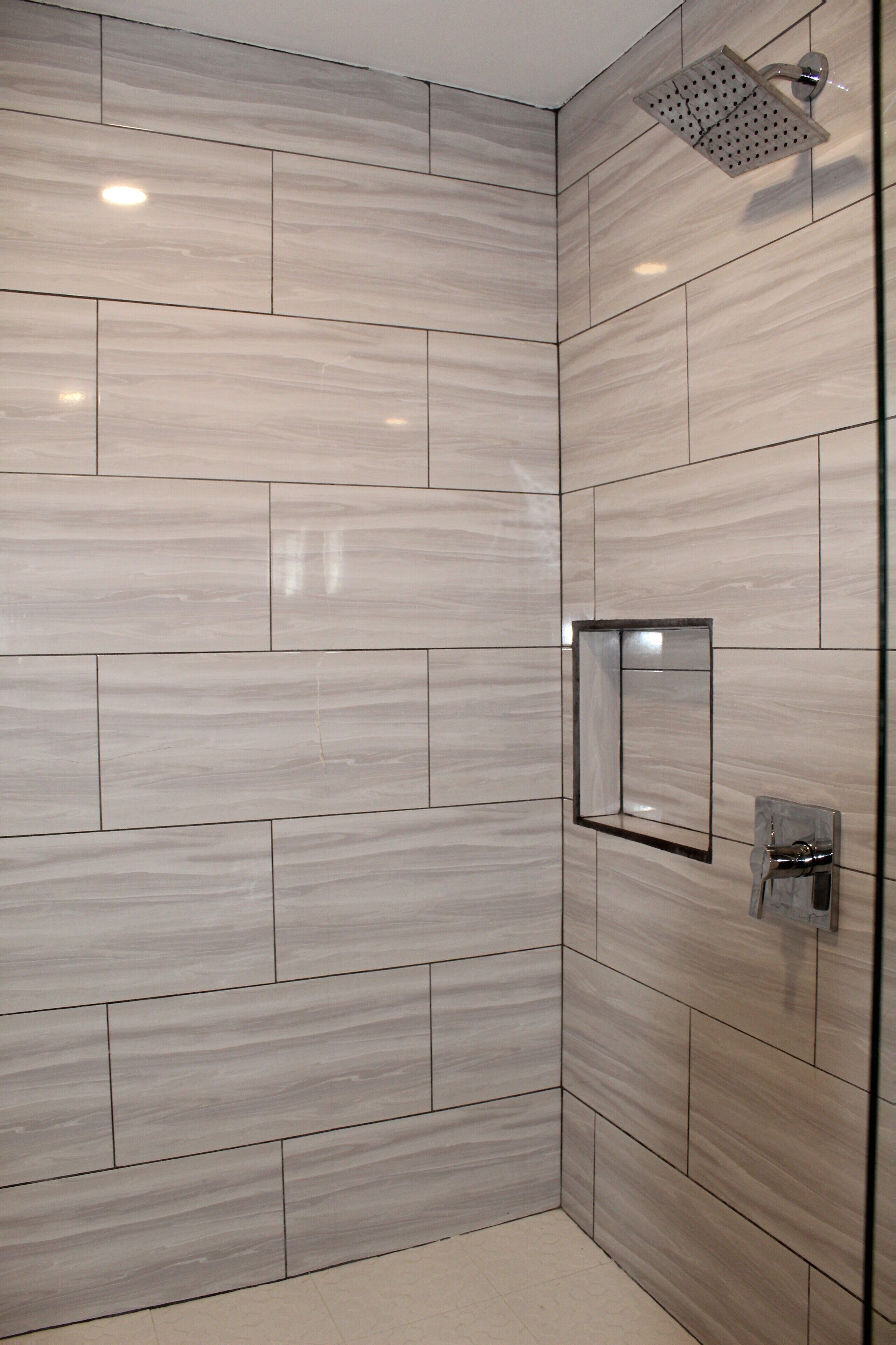 A modern bathroom with a shower, tiled walls, and a mirror.