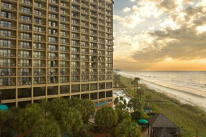 Un hotel moderno de altura con varios balcones que dan a una playa.