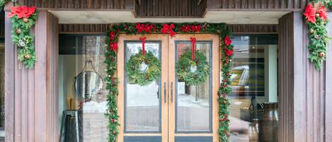 A building entrance with double doors, a doormat, and Christmas decorations.