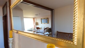 Ein Hotelzimmer mit großem Spiegel, einem Bett, einem Nachttisch, einer Lampe und einem fenster mit Vorhängen.