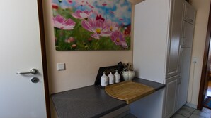 Eine Küche mit schwarzem Arbeitsplatz, einem Holzer Schneidebrett und einem Blumenbild an der Wand.