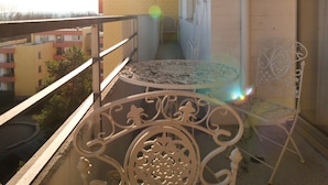 Ein Balkon mit eisenglattem Stuhl und Tisch, mit Blick auf ein Gebäude mit Backsteinfassade.