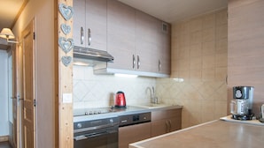 A modern kitchen with wooden cabinets, a stainless steel range, a red kettle, and a coffee machine.