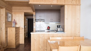A wooden kitchen with a central island, cabinets, and a dining table with chairs.