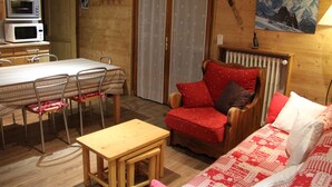 A cozy room with a wooden interior, a dining table with chairs, a red armchair, and a sofa. - 2-bedroom apartment near the slopes with terrace and garage in La Clusaz (La Clusaz)