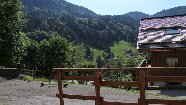 A wooden deck with a railing overlooking a valley with houses and a mountain backdrop. - 2-bedroom apartment near the slopes with terrace and garage in La Clusaz (La Clusaz)