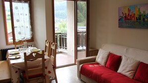 A dining area with a table set for two, a sofa, and a painting on the wall. - Renovated 2-bedroom apartment, station center, WIFI (La Clusaz)