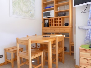 A wooden dining table with chairs, a microwave, and a coffee maker on a wooden shelf unit. - Family apartment 6 pax, south balcony, near Méribel (Méribel)
