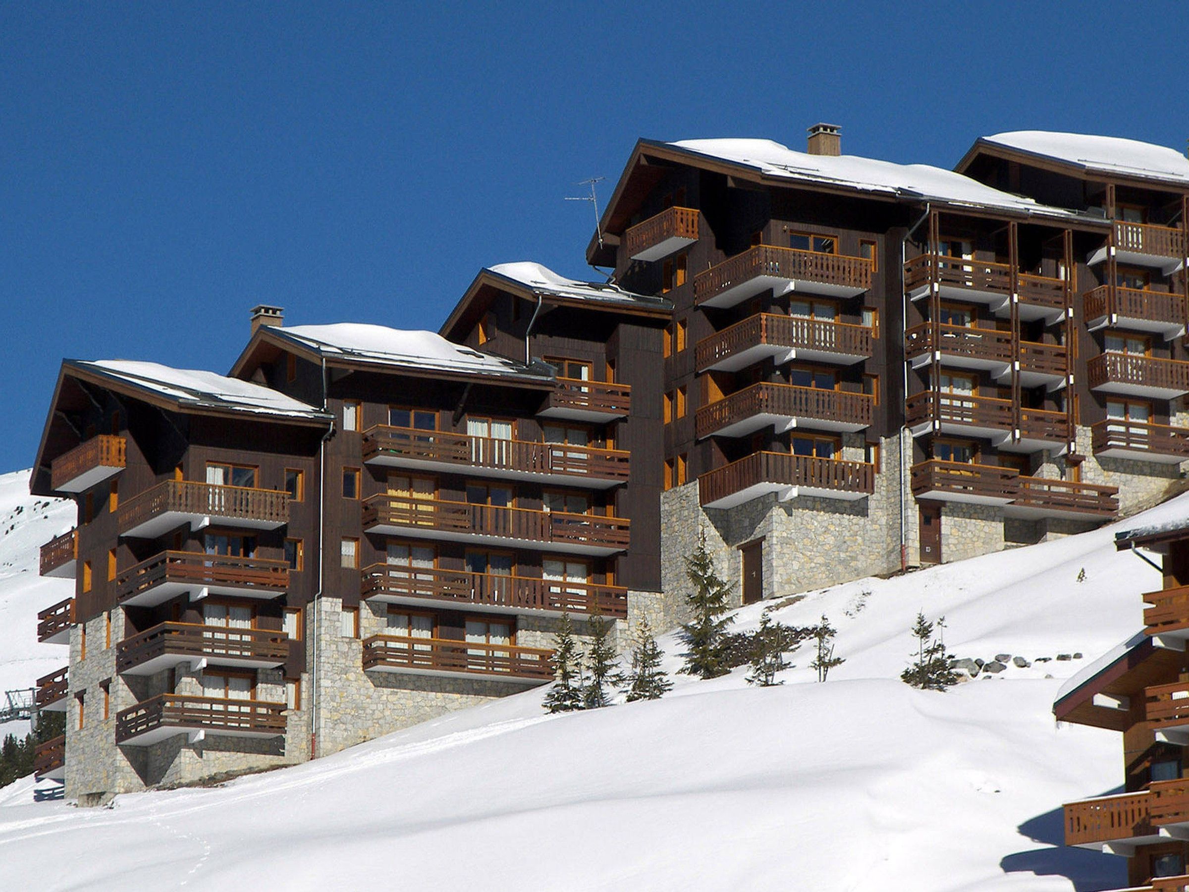 Ein mehrstöckiges Hotel mit Balkonen, vor verschneiter Landschaft.