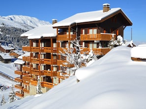 A multi-story wooden chalet with balconies, surrounded by snow-covered mountains and trees. - Family apartment 6 pax, south balcony, near Méribel (Méribel)