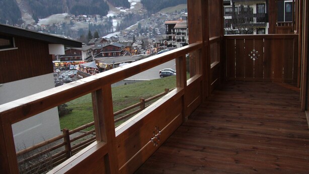 Ein Holzbalkon mit Blick auf eine Bergstadt und eine Straße.