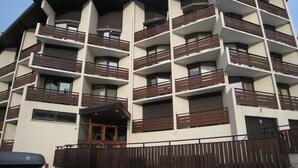 A multi-story hotel with balconies, a central entrance, and a gated driveway. - 2-Room Apartment, Ski-In/Ski-Out, South Balcony, Comfort for 6 (La Clusaz)