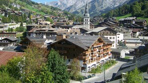A traditional European village with historic buildings, a prominent church tower, and mountainous backdrop. - 2-Room Apartment, Ski-In/Ski-Out, South Balcony, Comfort for 6 (La Clusaz)