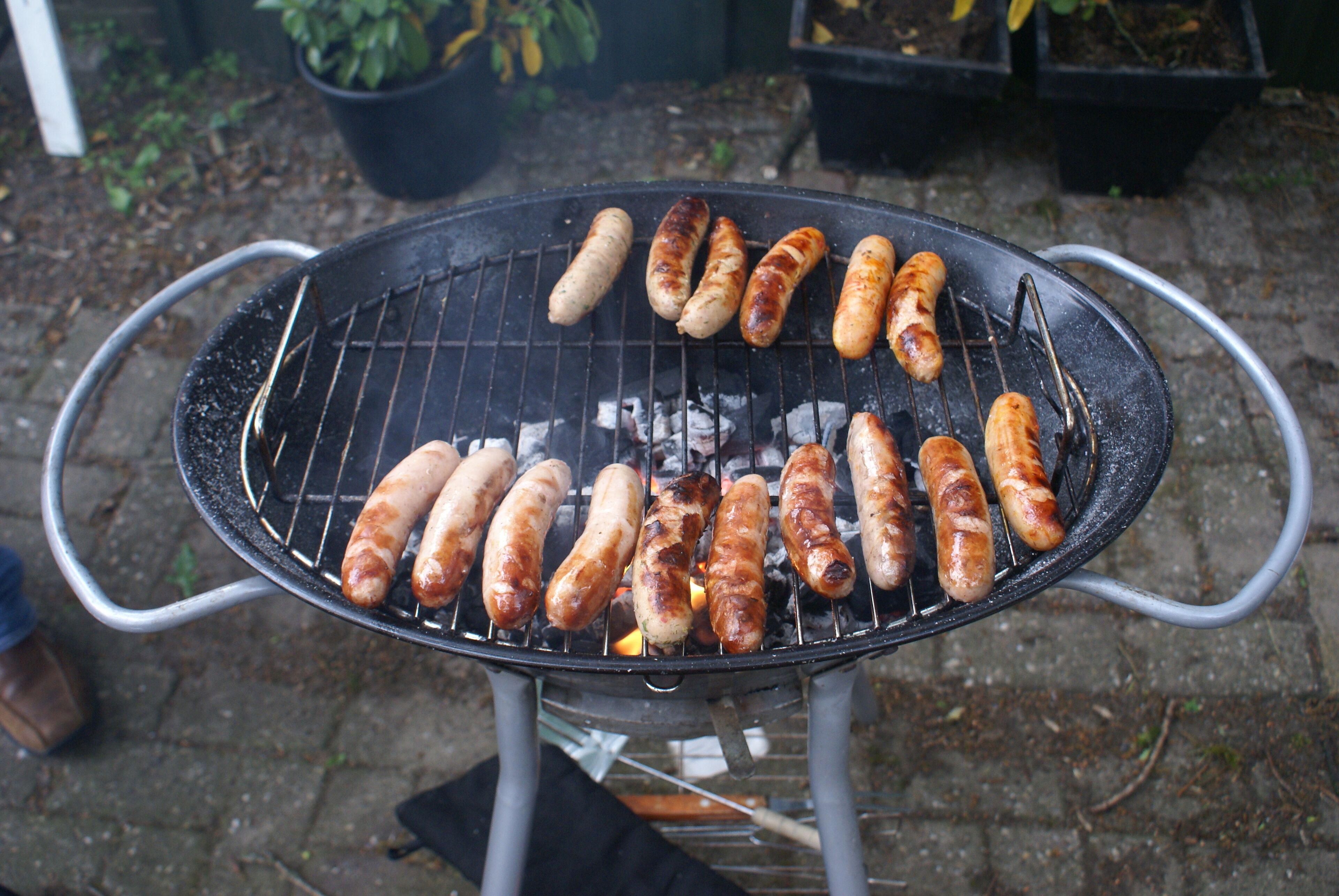 A grill with sausages being cooked outdoors.