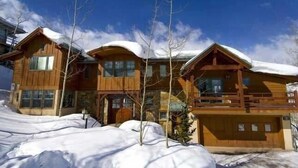 A wooden cabin with a balcony, surrounded by snow.
