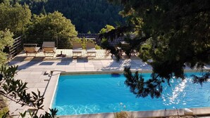 A swimming pool with lounge chairs and a view of a mountainous landscape. - Charming dry-stone house, perfect holidays (Saumane-De-Vaucluse)