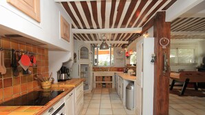 A kitchen with a tiled backsplash, wooden cabinets, and a central island. - Charming dry-stone house, perfect holidays (Saumane-De-Vaucluse)