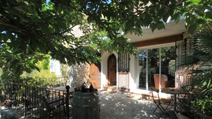 A patio area with a stone floor, wooden furniture, and a large barrel. - Charming dry-stone house, perfect holidays (Saumane-De-Vaucluse)