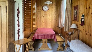Ein Holzblockhaus-Interieur mit Esstisch, Bank und einem Bett.
