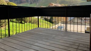Eine Holzterrasse mit Blick auf eine gebirgige Landschaft, einschließlich einer Seilbahn und Gebäuden.