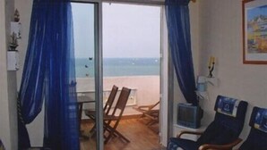 Een kamer met uitzicht op het strand, een televisie en twee stoelen.