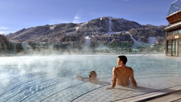 Ein Thermalbecken mit Blick auf schneebedeckte Berge.