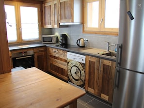A kitchen with wooden cabinets, a stainless steel refrigerator, a microwave, a coffee maker, and a dishwasher.