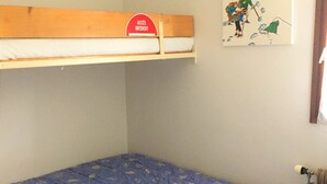 A bunk bed with a red sign above it, a blue mattress with leaf patterns, and a wall-mounted picture of hikers. - 1-bedroom near slopes with balcony (La Clusaz)