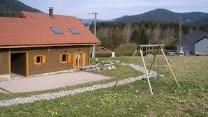 Una casa con techo rojo, dos tragaluces y fachada de madera.