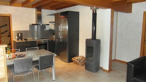 Una cocina moderna con estufa integrada, electrodomésticos de acero inoxidable y un comedor con sillas y mesa.