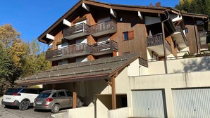 A multi-story building with wooden balconies and a covered parking area. - Cozy 2-Room Apartment with Balcony and Mountain View in La Clusaz (La Clusaz)