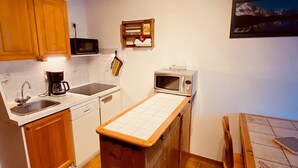 A compact kitchen with wooden cabinets, a microwave, a coffee maker, and a small sink. - Cozy 2-Room Apartment with Balcony and Mountain View in La Clusaz (La Clusaz)