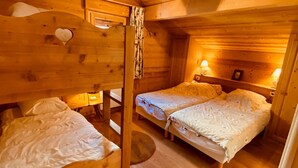 Une chambre confortable, aménagée comme un chalet, avec deux lits superposés et un petit espace bureau.