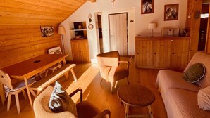 L’intérieur chaleureux d’un chalet comprend une table à manger en bois, des chaises, un canapé et une petite table ronde.
