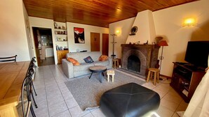A cozy living room with a fireplace, a sofa, a coffee table, and a TV stand. - 3-room apartment with balcony, fireplace, and Wifi in La Clusaz (La Clusaz)