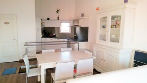A compact kitchen with a dining area, a built-in oven, and a white cabinet with glass doors. - Beautiful duplex design air-conditioned single storey facing the sea (Monticello)