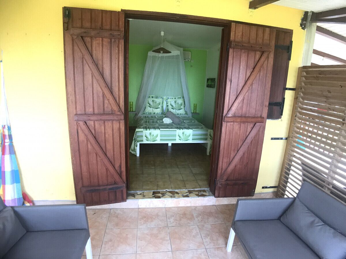 A room with a bed, a chair, and a wooden door.