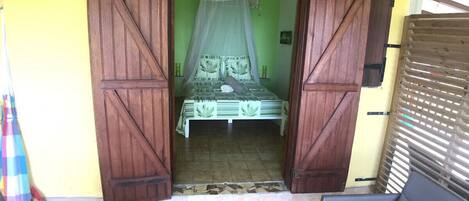 A room with a bed, a chair, and a wooden door.