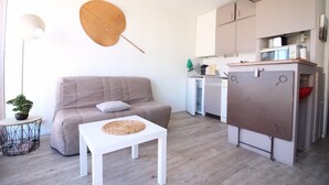 A compact living space with a sofa, a small table, a kitchenette, and a dining area. - for rent studio gruissan (gruissan)