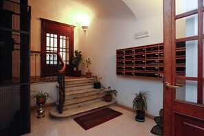 A staircase with potted plants, a wall-mounted wine rack, and a door with glass panels. - Piazza di Spagna, Fontana di Trevi, Colosseo all by feet !  (Roma)