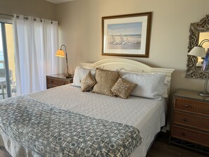A neatly made bed with patterned bedding, a framed picture above it, and a side table with a lamp. - 𝔾𝕦𝕝𝕗𝔽𝕣𝕠𝕟𝕥 𝑬𝒎𝒆𝒓𝒂𝒍𝒅 𝑰𝒔𝒍𝒆 9th Floor Stocked & Stellar Reviews! (Unknown)