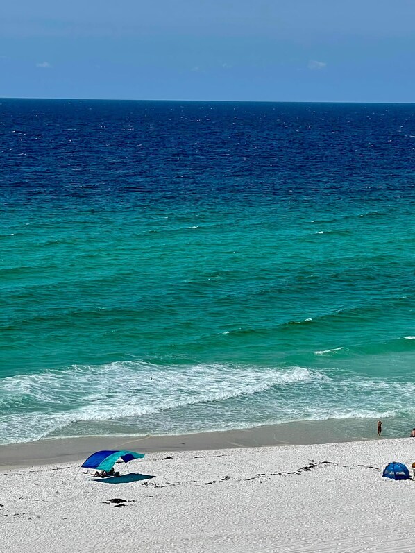 A beach with clear turquoise water, a sandy shore, and a few umbrellas. - 𝔾𝕦𝕝𝕗𝔽𝕣𝕠𝕟𝕥 𝑬𝒎𝒆𝒓𝒂𝒍𝒅 𝑰𝒔𝒍𝒆 9th Floor Stocked & Stellar Reviews! (Unknown)