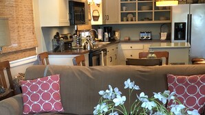 A living room with a sofa, a coffee table with magazines, and a vase with flowers.