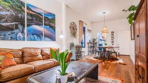 A living room with a leather sofa, a coffee table with a plant, and a dining area with a table and chairs.